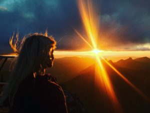 Vue de dos d'une femme regardant un coucher de soleil flamboyant