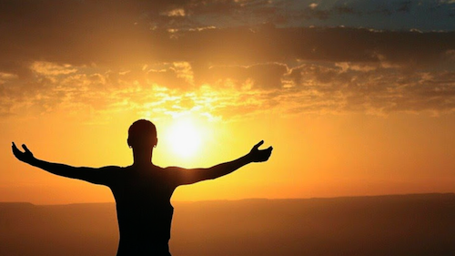 homme bras ouverts face au soleil