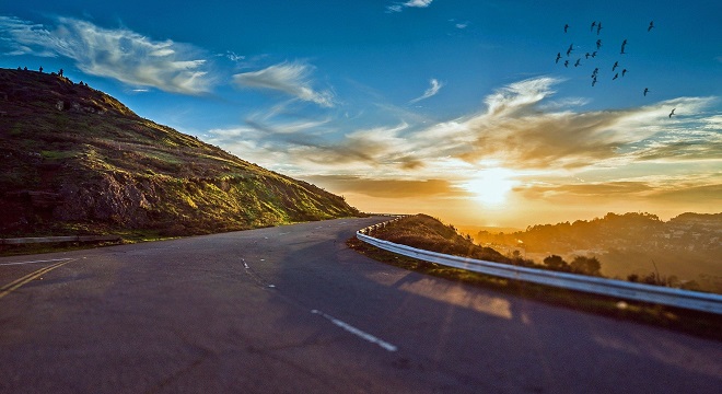 Route de montagne disparaissant dans un coucher de soleil