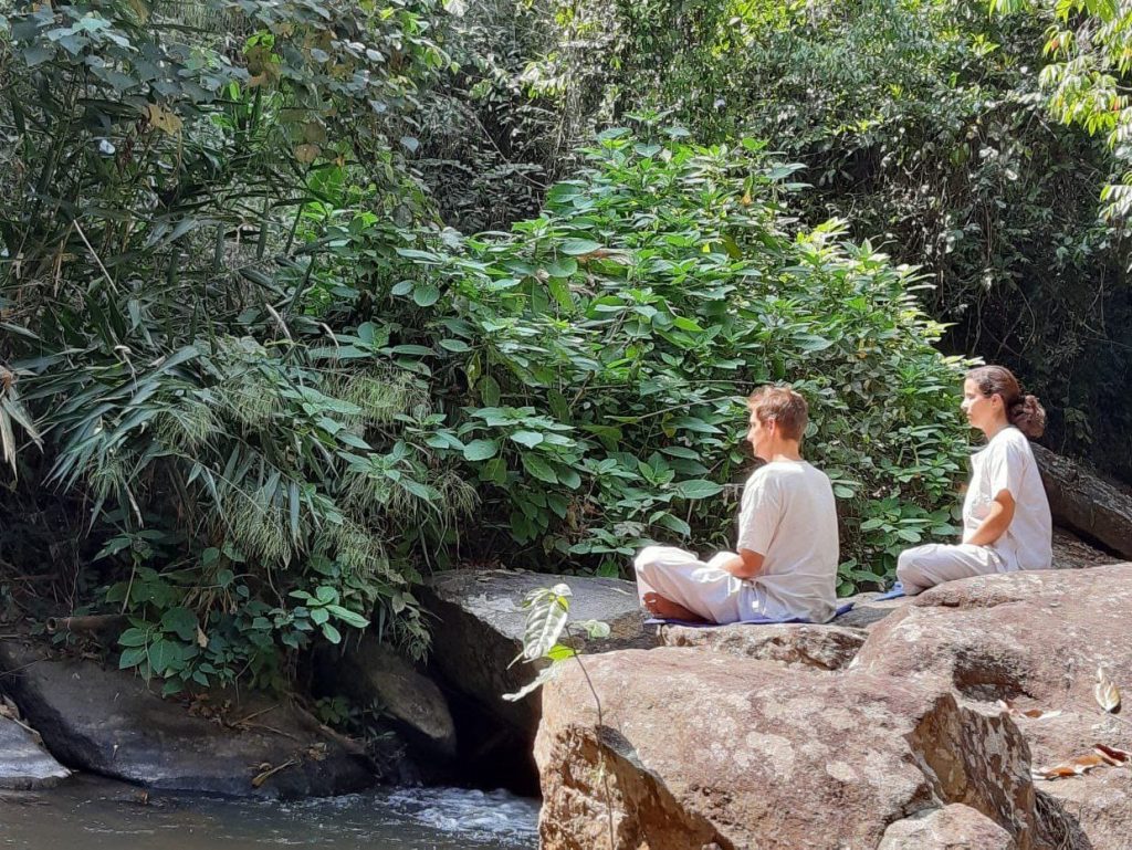 Deux personnes assises sur un rocher qui surplombe une rivière