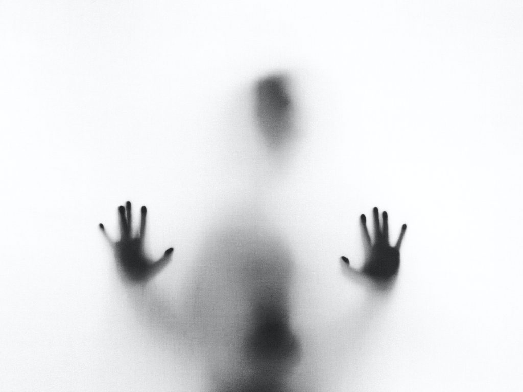 Silhouette d'un homme presque transparente avec des nuances de noir et de gris, paumes de mains placées de face et davantage visibles.
