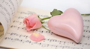 Un coeur et une rose posés sur une partition de musique