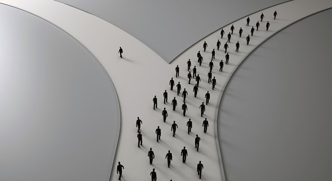 Deux routes qui se séparent vues d'en haut et une personne prend un chemin différent du reste de la foule