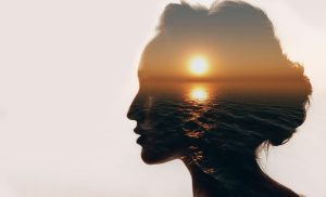 Photo montage montrant un visage de femme de profil avec un coucher de soleil sur l'océan à l'intérieur