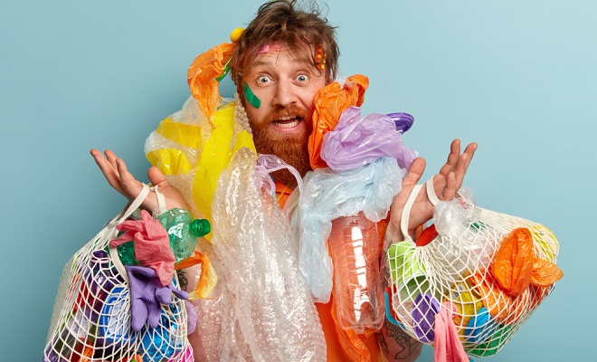 Un homme submergé par tout sorte de déchets plastiques