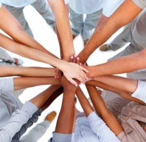 Plusieurs personnes qui réunissent leurs mains, formant une étoile.