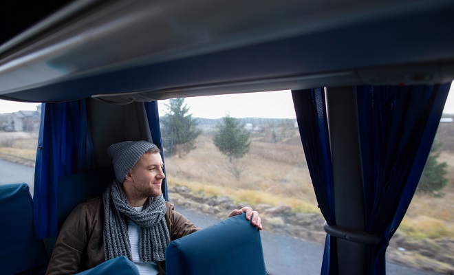 Un jeune homme regarde le paysage par la fenêtre d'un autocar