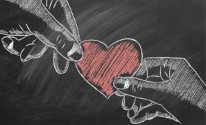 Dessin à la craie de deux mains partageant un cœur