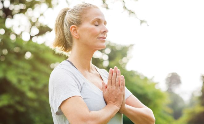 Une femme les mains jointes et les yeux fermés comme reconnaissante envers la vie