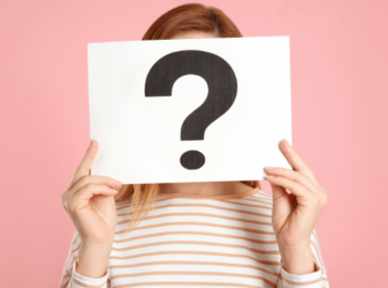 Une femme dont le visage est caché par un écriteau avec un gros point d'interrogation