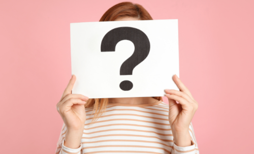 Une femme dont le visage est caché par un écriteau avec un gros point d'interrogation