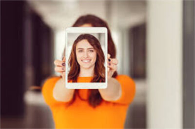 Une femme tenant une photo de son visage, devant son visage