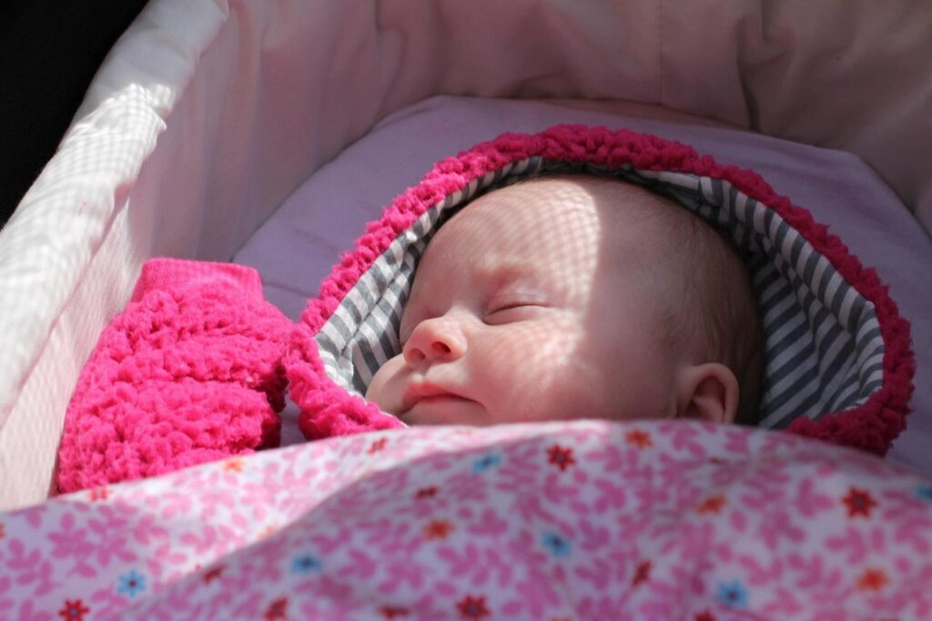 Un bébé endormi, dans un landeau.