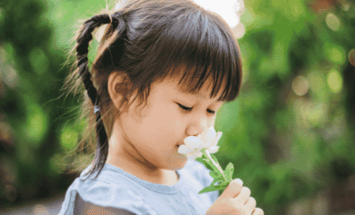 Une fillette les yeux fermés en train de sentir une fleur