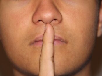 homme qui met son index devant ses lèvres pour faire silence