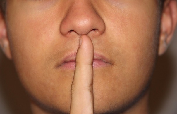 homme qui met son index devant ses lèvres pour faire silence