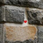 Mur en pierre avec un petit coeur rouge au centre