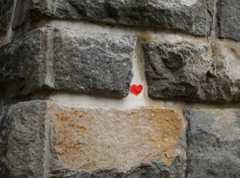 Mur en pierre avec un petit coeur rouge au centre