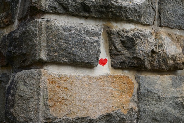 Mur en pierre avec un petit coeur rouge au centre