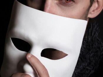 Homme qui cache une partie de son visage derrière un masque blanc
