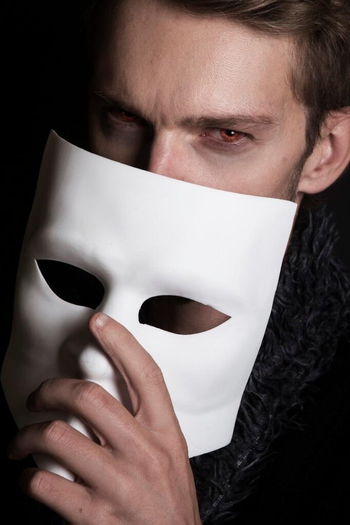 Homme qui cache une partie de son visage derrière un masque blanc
