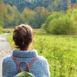 Une femme de dos qui se ballade le long d'un chemin