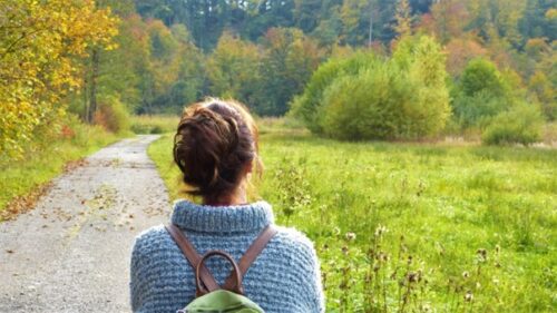 Une femme de dos qui se ballade le long d'un chemin 