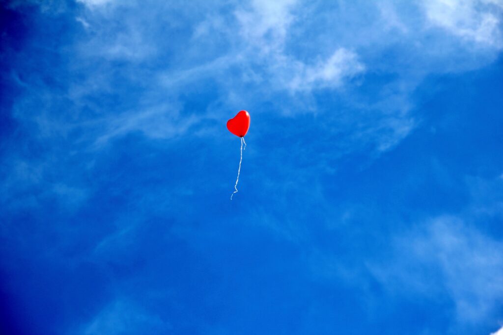 ballon rouge en forme de coeur lâché dans le ciel