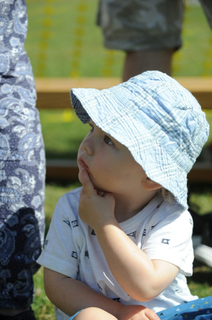 enfant avec un chapeau qui regarde au loin et semble réfléchir