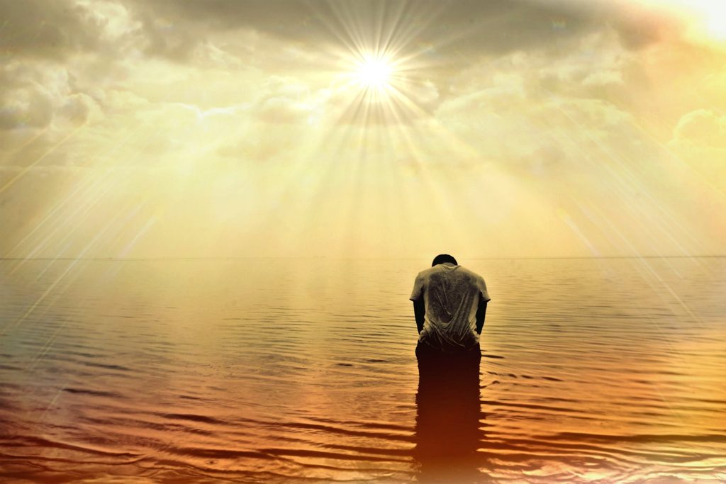Homme tête baissée face au soleil et ses rayons