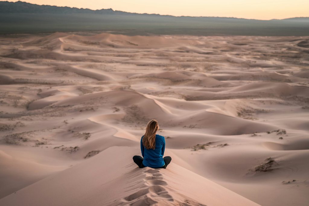 femme assise sur le sable regardant au loin.