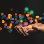 Main paume vers le haut entourée d'étincelles de lumières