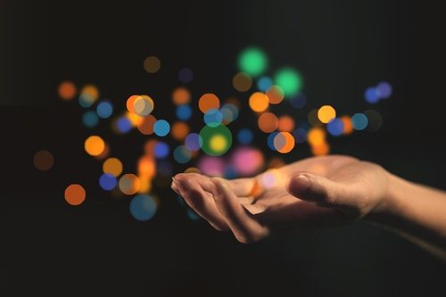 Main paume vers le haut entourée d'étincelles de lumières