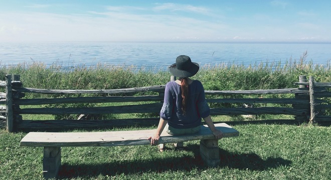 Femme assis sur un banc, regardant la mer